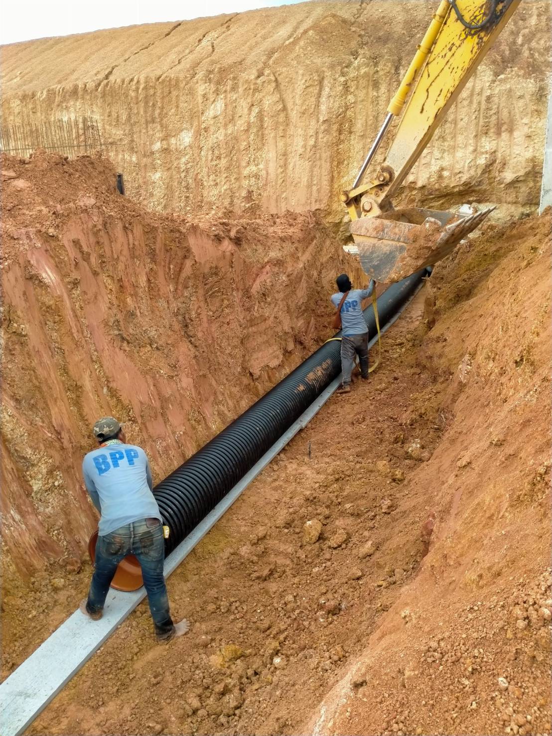 The engineer is using a backhoe to install corrugated pipes ( TAPKORR) underground at the industrial estate