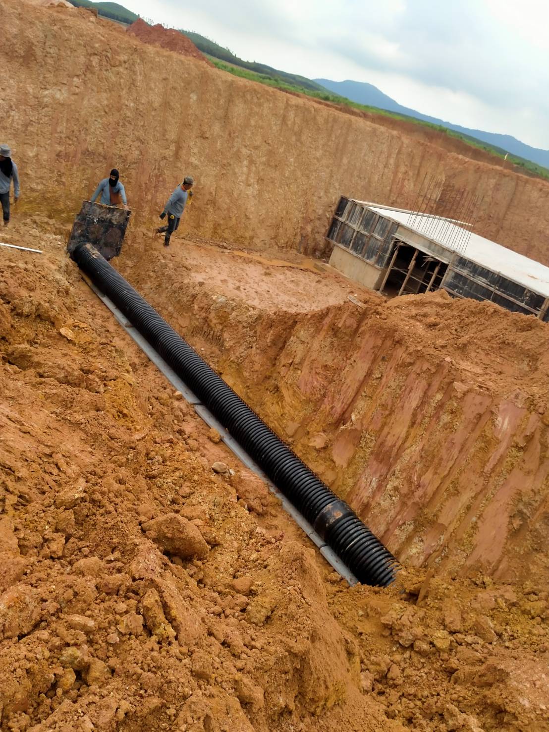 The engineer is laying corrugated pipes ( TAPKORR ) in the industrial estate using the trench installation method