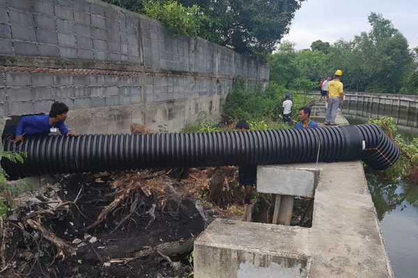 Engineer installing a drain pipe made of TAPKORR pipe into the river.