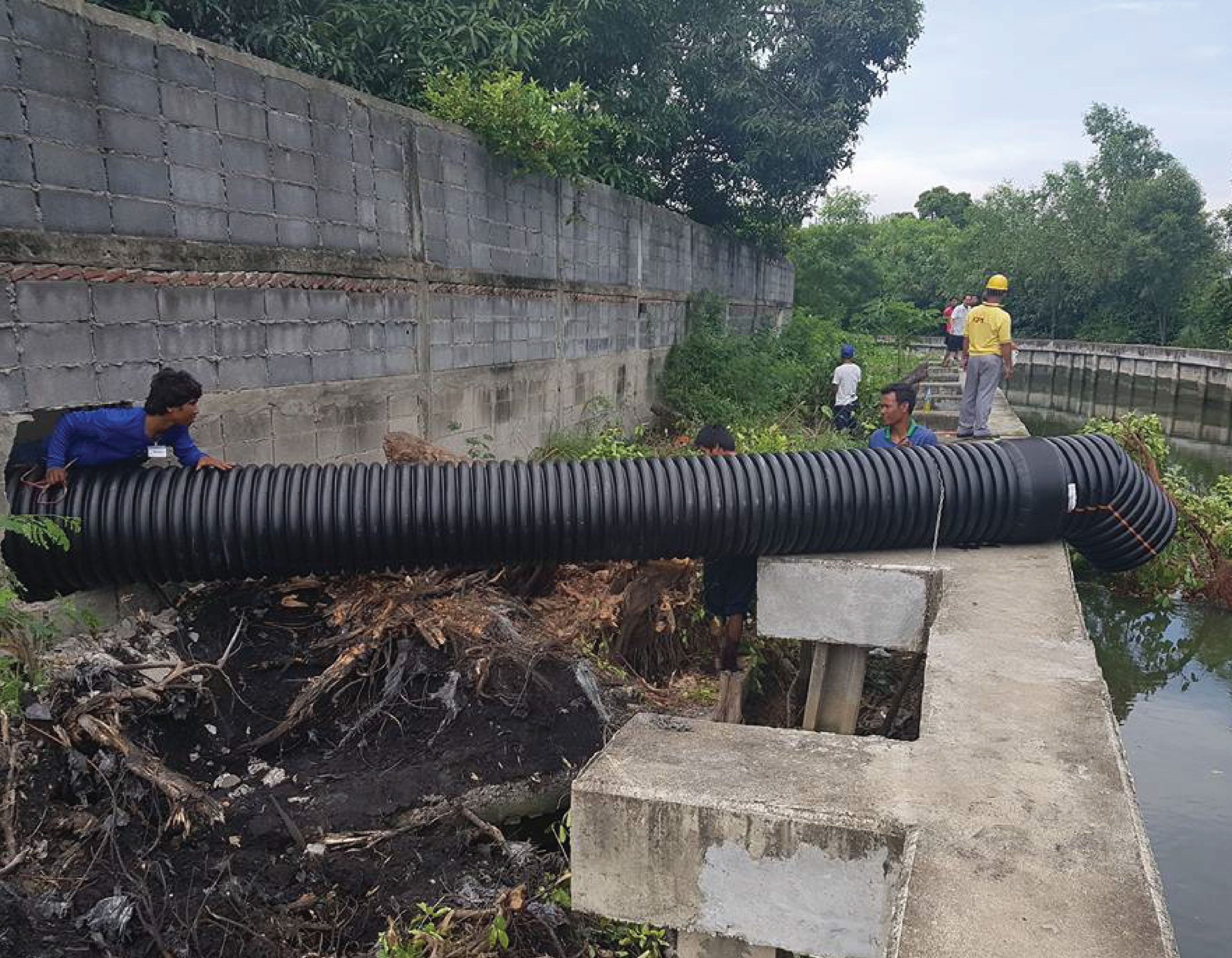 Engineer installing a drain pipe made of TAPKORR pipe into the river.