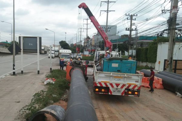 Engineers using a jaw crane to install HDPE pipes in a trench installation at Thaioil plant.