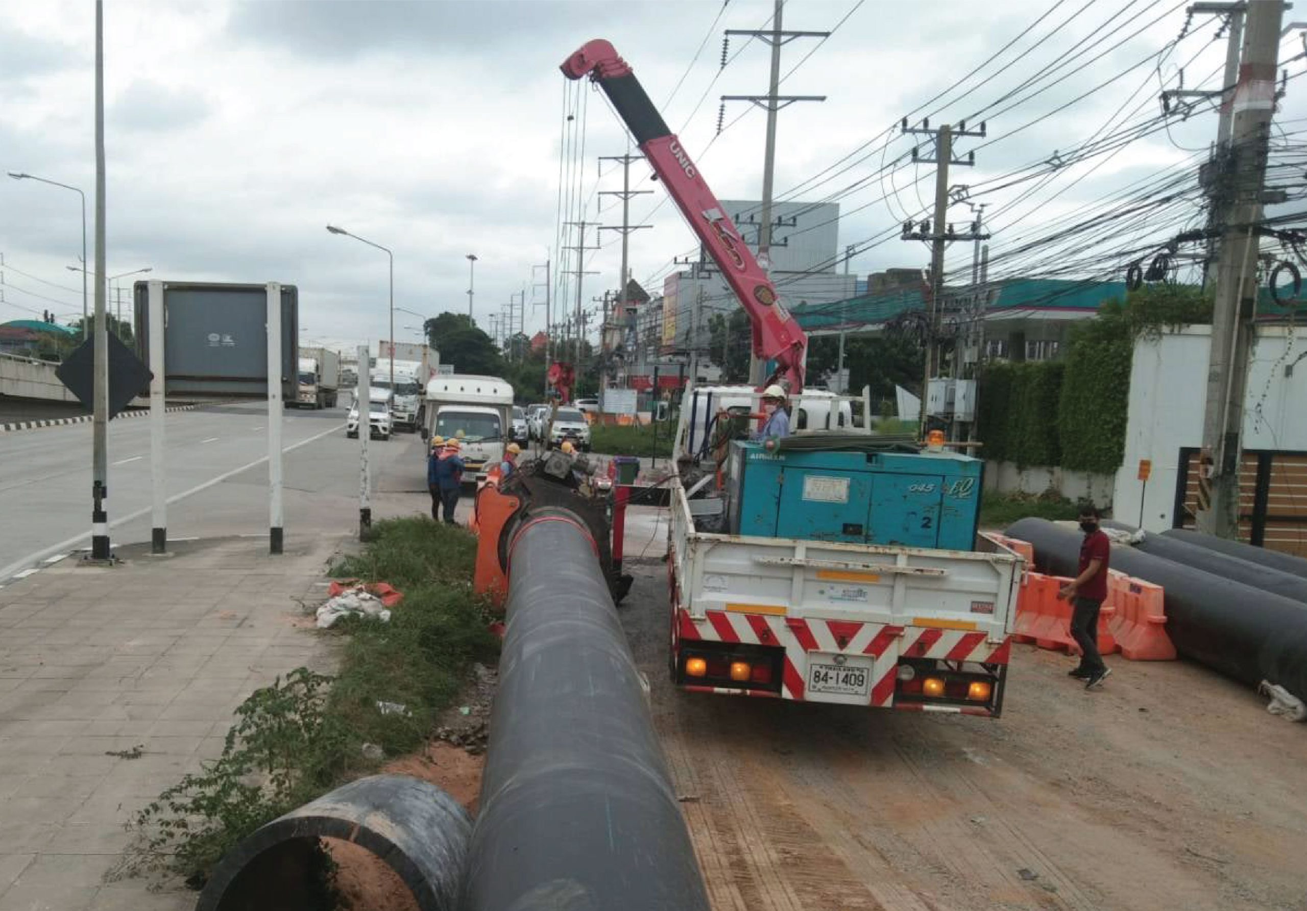 Engineers using a jaw crane to install HDPE pipes in a trench installation at Thaioil plant.