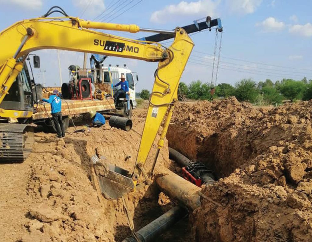 Blackhoe digging trenches for installation HDPE pipes to solve drought in Buriram Province