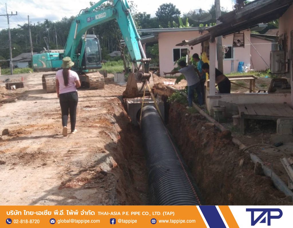 Backhoe is laying HDPE pipe to line the manhole-to-manhole connection with other pipes