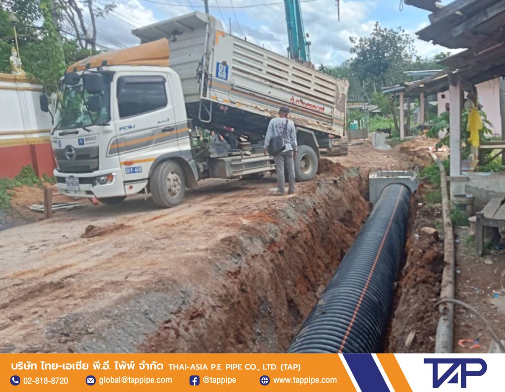 Earthmoving truck pours soil to cover the trench from the deep trench HDPE pipe installation