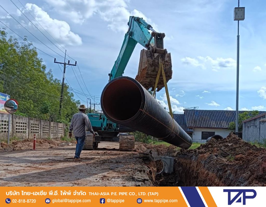 Backhoe lifts HDPE pipe to lay the pipe into the trench